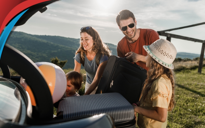 Passengers load luggage into the trunk of a sleek minibus.